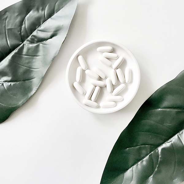 PIlls in a dish, surrounded by leaves